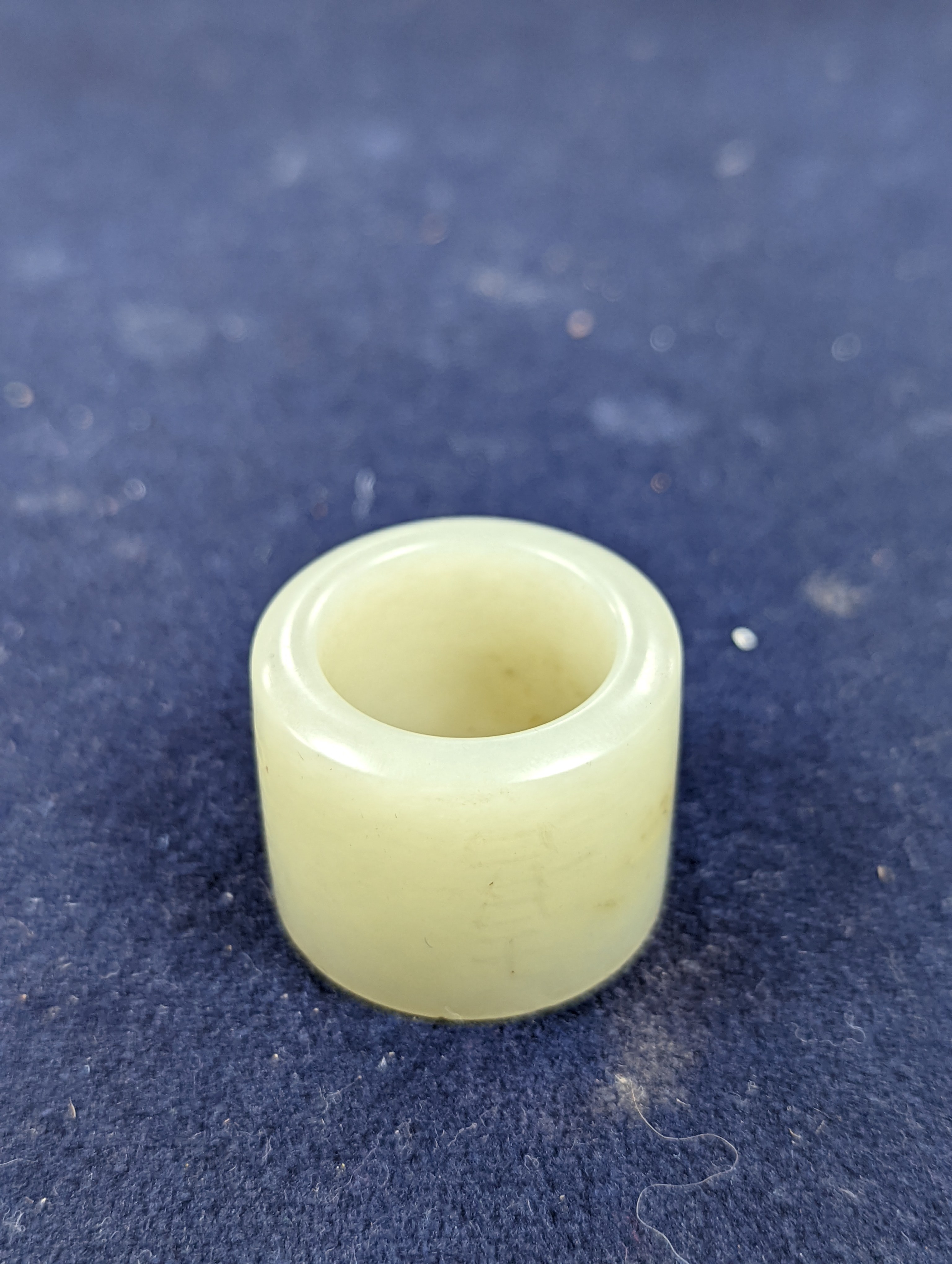A 19th century Chinese pale celadon jade archer’s thumb ring, inscribed, 3 cm diameter
